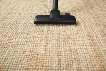 Hoovering beige carpet with modern vacuum cleaner. Space for text