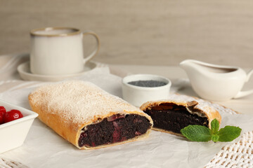 Delicious strudel with cherries and poppy seeds on table, closeup