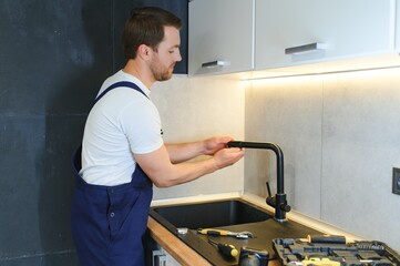 Professional plumber fixing water tap in kitchen