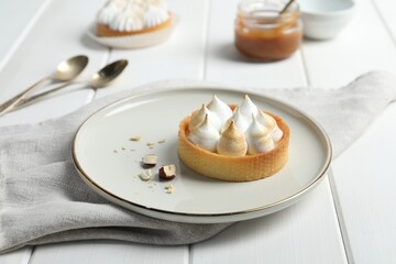 Tartlet with meringue on white wooden table. Delicious dessert