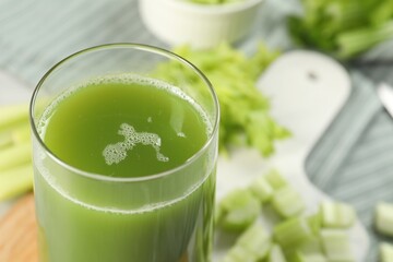 Glass of delicious celery juice and vegetables on wooden board, closeup. Space for text