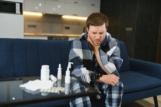 Rhinitis, Medicine And Healthcare Concept - Sick Man In Blanket Using Oral Spray At Home.