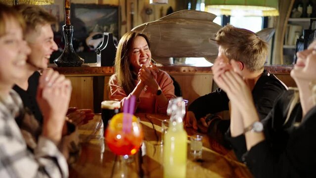 Group of happy multiethnic friends having fun together, drinking bottled beer in a bar or at home, celebrating, happily smiling - friendship, togetherness concept