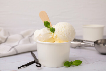 Delicious ice cream with mint and vanilla pods on white textured table, closeup