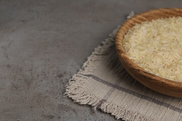 Fototapeta na wymiar Bowl of raw rice on grey table. Space for text