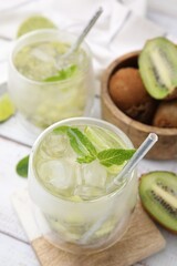 Obraz na płótnie Canvas Refreshing drink with kiwi and mint on white table, closeup