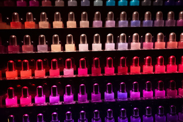 Fototapeta premium A collection of nail polish glass bottles is expertly arranged on a shelf, showcasing a captivating gradient of vibrant colors. Generative AI.