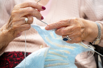 Elderly woman crocheting in a handicraft course as a hobby or occupational therapy at nursing home....