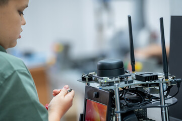 Boy male teen child concentrate enjoy Machine Learning Robot is Moving Under Control robot coding at technology stem class, stem education robot for digital automation artificial intelligence ai
