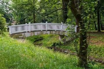 A white bridge with a wooden balustrade in the city park in Skierniewice