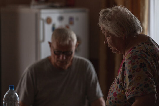 Elderly male and wonan in casual clothes be near the dining table with a bottle and products in light kitchen