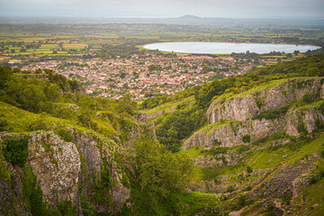 Fototapeta na wymiar Cheddar Gorge with Cheddar Village and reservoir at dawn on a cloudy humid morning in summer. Somerset, England