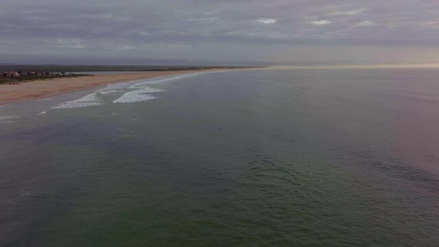 Africa drone aerial cinematic dolphins pod swimming sunrise sunset early morning ocean surf waves JBAY Jefferys Bay Indian Ocean deep aqua blue water cloudy golden backward from shore movement
