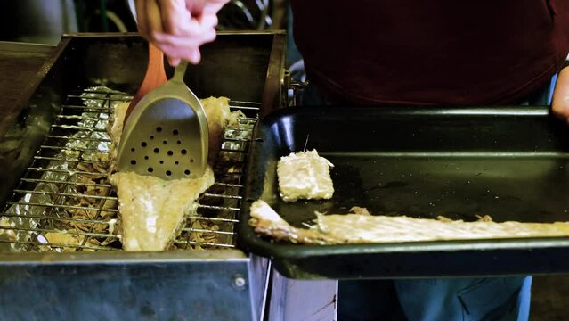 Cooked snoek seafood being moved from smoker with utensils to serving tray