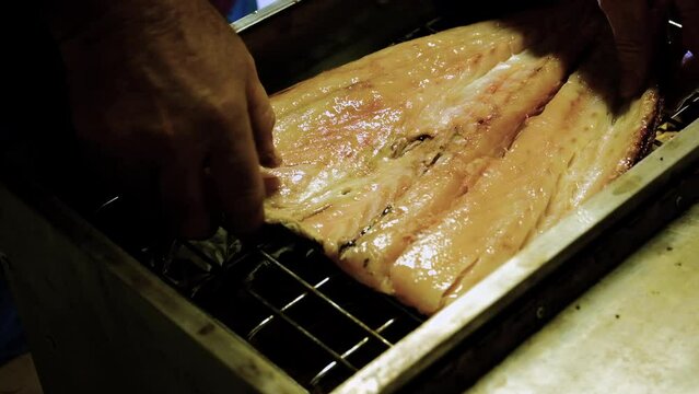 Gutted and butterflied snoek placed on grid in stainless steel smoker