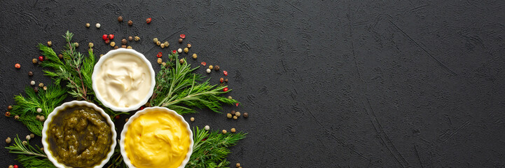 Different types of sauces in bowls with seasonings banner, rosemary and dill, thyme and and peppercorns, top view, copy space