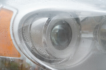 A front car headlight with water condensation inside. A typical problem with condensation in auto headlights.
 - obrazy, fototapety, plakaty