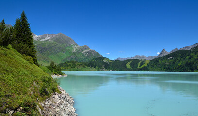 Naklejka na ściany i meble Reservoir lake with mountains epic landscape. Idyllic reservoir Kops lake at 1800 m in austrian Galtur, Vorarlberg