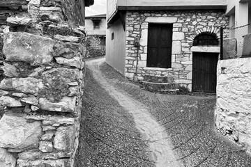 Narrow steep street in a greek village with stone walls houses. - 615417146