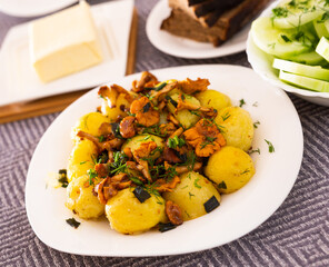 baked potatoes with chanterelles, served with herbs on white plate