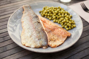 Fried trout fillets served with green peas