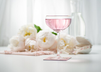 Pink rose lemonade in a sparkle glass with white peony bouquet on a background
