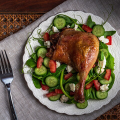 Roast duck salad with pea tendrils, cucumber, chopped tomatoes, and feta cheese.
