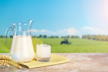 Tasty fresh milk on wooden table in meadow