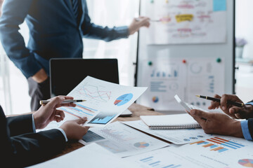 Group of business people working together on new project with planning analytical report at meeting. Businesspeople meeting together pointing to graph assess business profits.