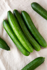 Organic Mini Baby Cucumbers on a white wooden background, top view. Flat lay, overhead, from above.