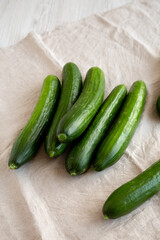 Organic Mini Baby Cucumbers on a white wooden background, side view.