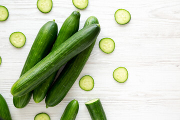 Organic Mini Baby Cucumbers on a white wooden background, top view. Flat lay, overhead, from above. Copy space.