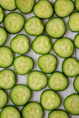 Sliced Organic Mini Baby Cucumbers on a white wooden background, top view. Flat lay, overhead, from above.