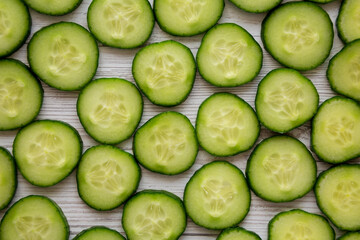Sliced Organic Mini Baby Cucumbers on a white wooden background, top view. Flat lay, overhead, from above.