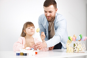 Obraz na płótnie Canvas Girl with Down syndrome and her father playing with Easter colored eggs