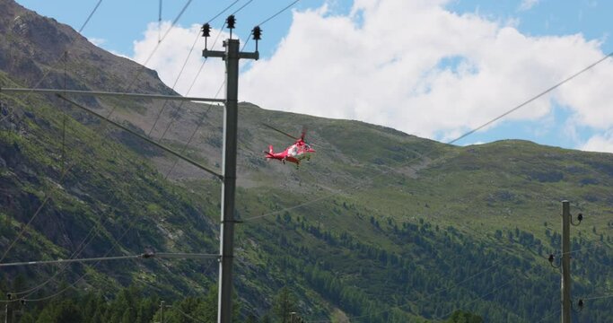 Swiss Air-Rescue helicopter taking off over busy road in Switzerland. Low angle pov