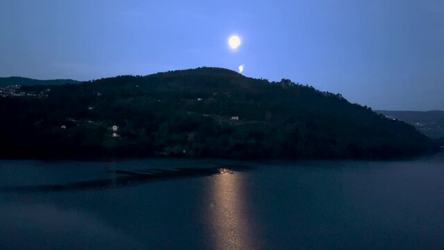 wide view of summer night and the moon by the Douro river lake in Portugal.