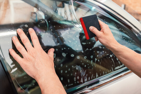 Car tinting windows - Worker specialist applying tint foil on car window
