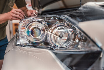 Car tinting service - Worker specialist apply tint foil on car headlight in workshop