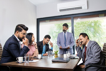 Stress situation in conference room, indian boss unhappy with the performance of his employees for...