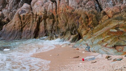 Sad beach. View of beach littered with plastic waste, sending our planet into next deadly wave of change. View of beautiful majestic cliffs on beach is spoiled by plastic waste. Garbage trash on beach