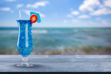 Tasty sweet alcohol cocktail in glass on beach background