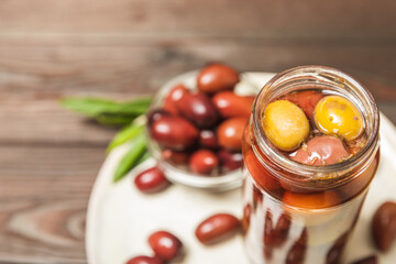 Pickled olives in glass jar. On a wooden background.Tasty olives on wooden table.Close-up.Place for text.Copy space. Delicious healthy mediterranean food.Vegan