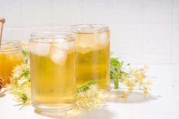 Organic herbal health drink. Linden plant flower green tea, in white mugs, with a teapot, on a white table, with copy space and blooming linden inflorescences and flowers