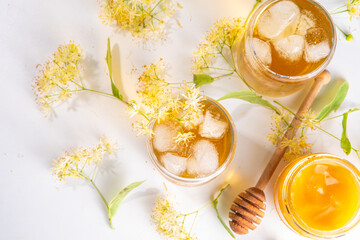 Organic herbal health drink. Linden plant flower green tea, in white mugs, with a teapot, on a white table, with copy space and blooming linden inflorescences and flowers
