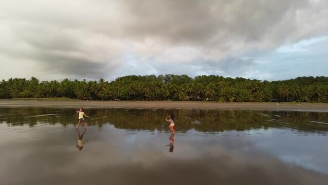 Two little girls in the beach, playing and running in the sand in a deserted tropical beach, Bejuco Beach, Costa Rica
