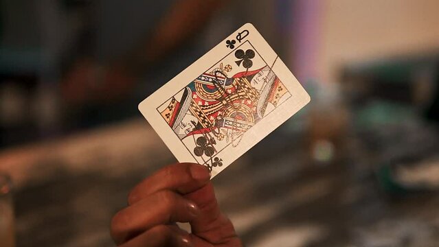 Slow motion dolly shot showing a signed queen of clubs playing card by a magician
