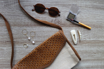 Fototapeta na wymiar Vintage bag, sunglasses, gold and pearl jewerly and glitter eyeshadow on wooden background. Flat lay.