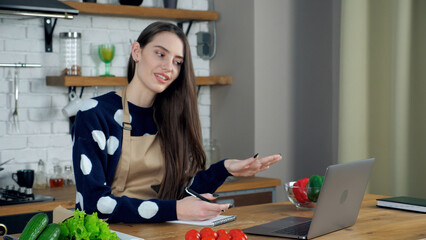 Smiling woman housewife in beige apron tells teacher study online remote video call conference...