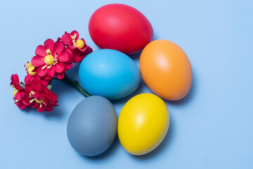 Colorful eggs, symbolizing Easter, on a colorful background and flowers